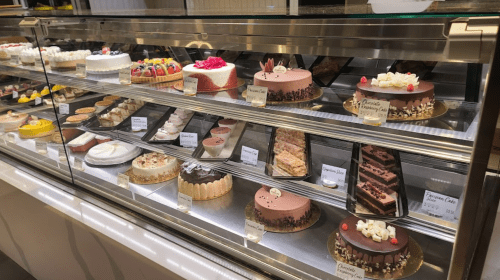 A display case filled with various colorful cakes and pastries, showcasing an assortment of desserts.