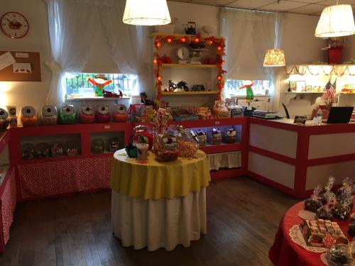 A colorful candy shop interior with jars of sweets, a round table, and festive decorations.