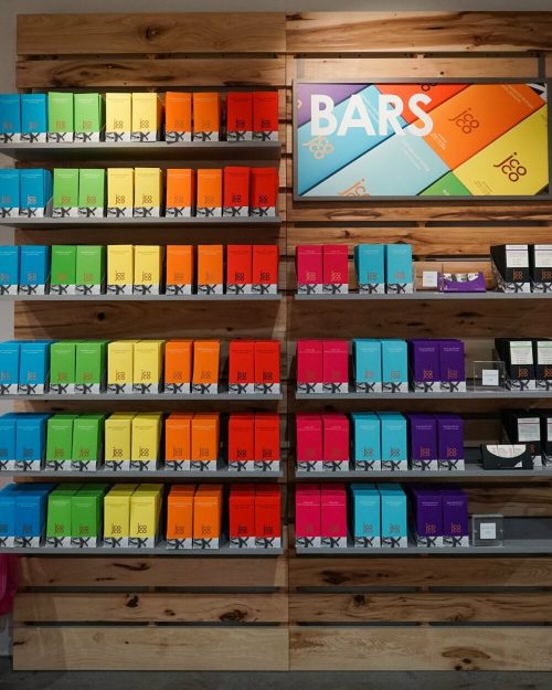Colorful display of snack bars on wooden shelves, featuring various flavors in vibrant packaging.