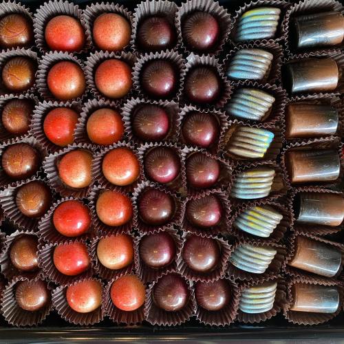 A variety of colorful chocolates arranged neatly in a box, featuring round and shaped confections.