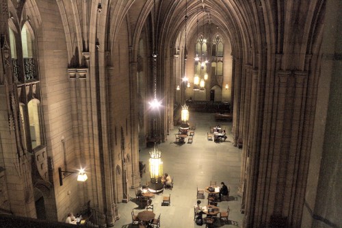 A spacious, dimly lit hall with high arches, tables, and soft lighting, creating a serene atmosphere.
