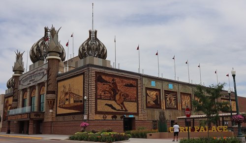 Exterior of a building with ornate architecture, featuring murals and decorative elements, under a cloudy sky.