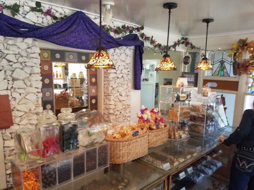A cozy candy shop interior with colorful jars, baskets of treats, and decorative lighting.