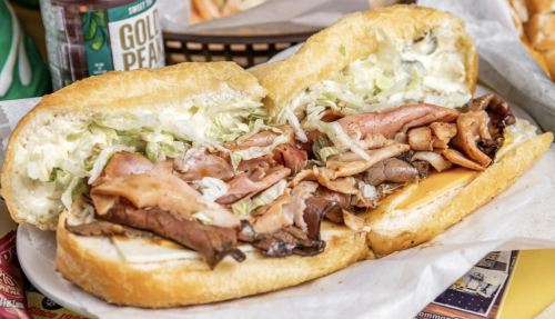 A hearty sandwich filled with layers of meats, cheese, and lettuce, served in a toasted hoagie roll.