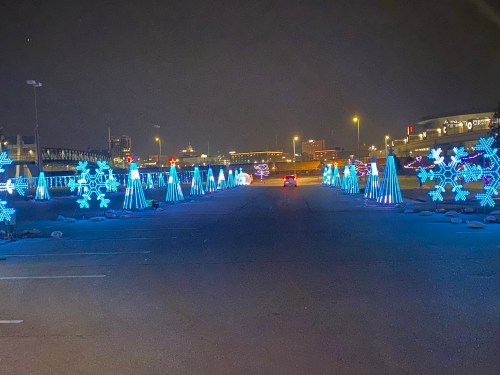 A nighttime scene of a road lined with blue holiday lights and snowflake decorations.