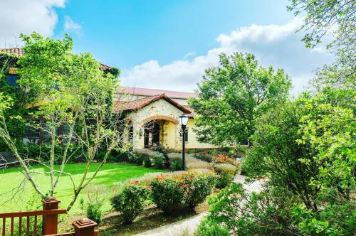 A sunny garden with lush greenery and blooming flowers surrounding a charming building.