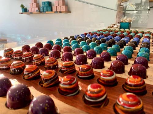 A colorful display of assorted chocolate truffles arranged in rows, showcasing various vibrant designs and patterns.