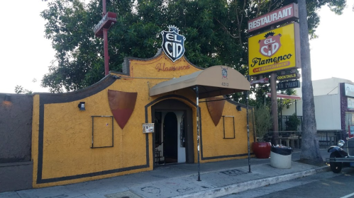 Exterior of El Cid Flamenco restaurant, featuring a bright orange facade and a large sign with the restaurant's name.