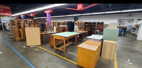 A spacious furniture store aisle filled with various wooden furniture pieces, including tables and cabinets.