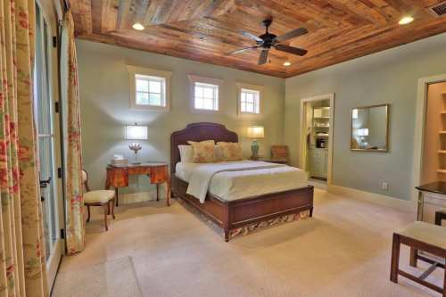 Cozy bedroom with a wooden ceiling, a queen bed, bedside tables, and natural light from windows.