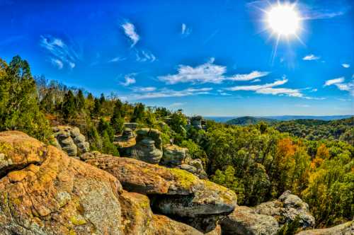 A panoramic view of rocky formations and lush trees under a bright blue sky with a shining sun.