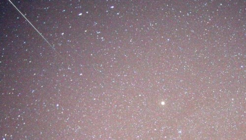 A starry night sky filled with twinkling stars and a faint streak of a meteor.