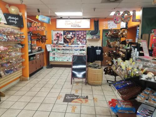 A colorful candy shop interior with shelves of sweets, a display case, and a welcoming sign for "Candy Land."