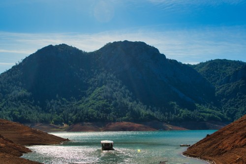 A serene lake surrounded by mountains, with a small boat floating on the water under a clear blue sky.
