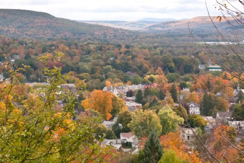 A scenic view of a colorful autumn landscape with trees in vibrant hues and a small town nestled in the valley.
