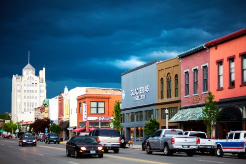 A street view of a small town with colorful buildings and dark storm clouds overhead.