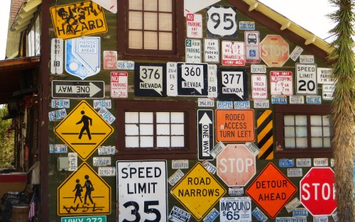 A colorful wall covered with various road signs, including speed limits, stop signs, and directional markers.