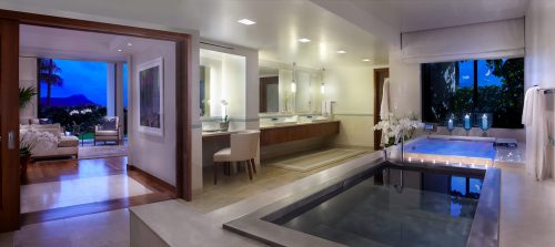 Luxurious bathroom with a soaking tub, modern decor, and a view of a serene outdoor space. Soft lighting enhances elegance.