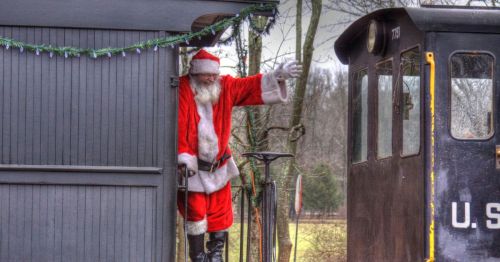 Santa Claus standing on a train waving.