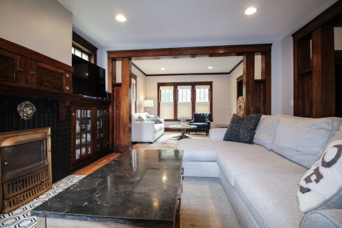 Cozy living room with a gray sectional sofa, marble coffee table, and wooden accents, featuring a fireplace and natural light.