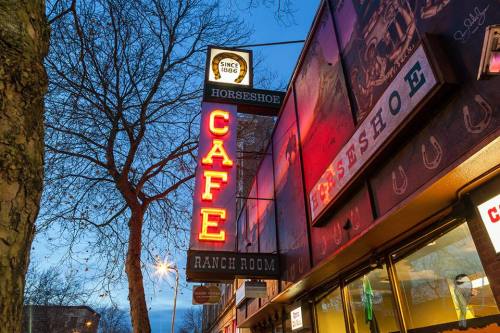 Neon sign for Horseshoe Cafe, featuring "Since 1866" and "Ranch Room," against a twilight sky.
