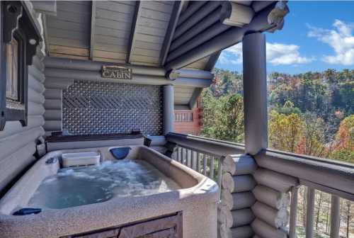 A hot tub on a cabin balcony with a scenic view of trees and blue sky in the background.