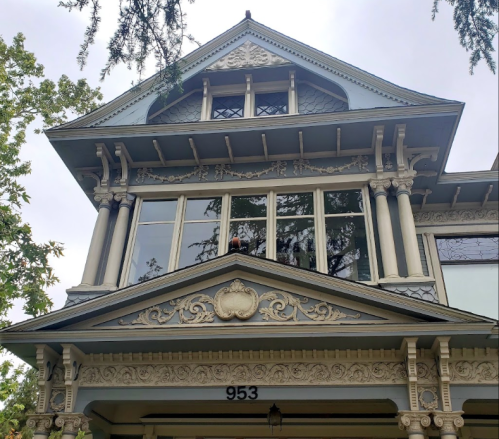 Victorian-style house with intricate architectural details and large windows, featuring ornate trim and a decorative facade.