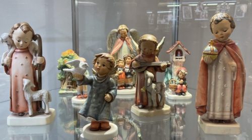 A display of ceramic figurines depicting children and angels in various poses, showcasing intricate details and colors.