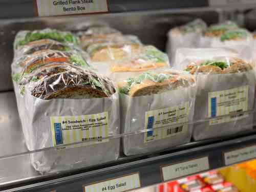 A display of pre-packaged sandwiches and salads in a refrigerated case at a store.