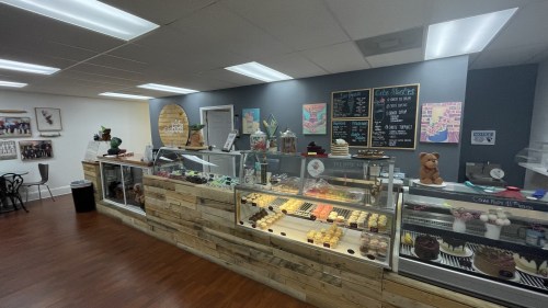 A cozy bakery display with various pastries and desserts, featuring a wooden counter and colorful menu boards.