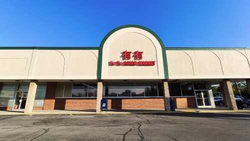 Exterior of an Asian market building with a green arch and red signage against a clear blue sky.