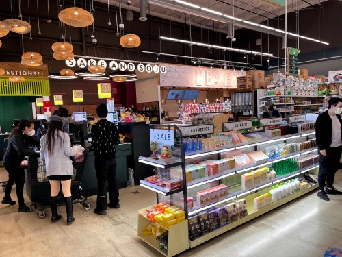 A vibrant store interior with shelves of products, a checkout area, and customers browsing in a lively atmosphere.