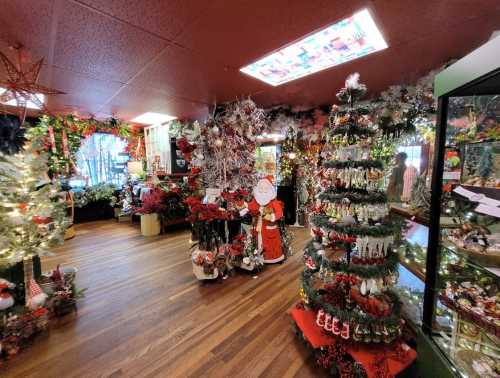 A festive shop filled with Christmas decorations, trees, and ornaments, featuring a Santa figure and colorful decor.