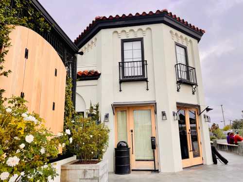 A stylish building with a curved facade, featuring wooden doors, balconies, and decorative elements, surrounded by greenery.