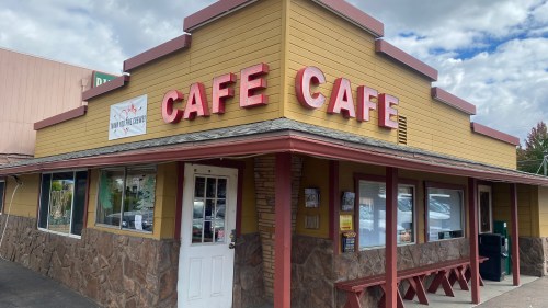 A yellow cafe building with "CAFE CAFE" signage, featuring stone accents and large windows.
