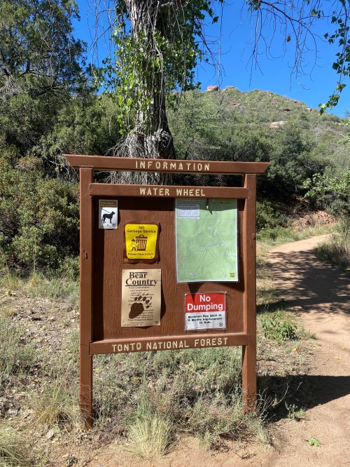 Information sign at Water Wheel in Tonto National Forest, featuring maps and notices about bear country and dumping regulations.