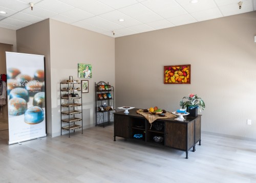 A cozy shop interior featuring a display table, shelves with items, and colorful artwork on the walls.
