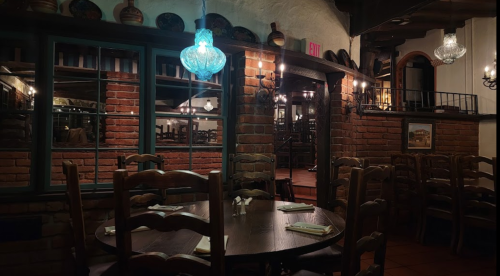 Cozy restaurant interior with wooden tables, brick walls, and decorative lighting, creating an inviting atmosphere.