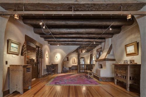 A cozy interior with wooden beams, art on the walls, and a colorful rug, creating a warm, inviting atmosphere.