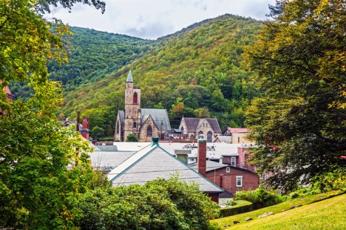 A scenic view of a church nestled among green hills and buildings in a small town.