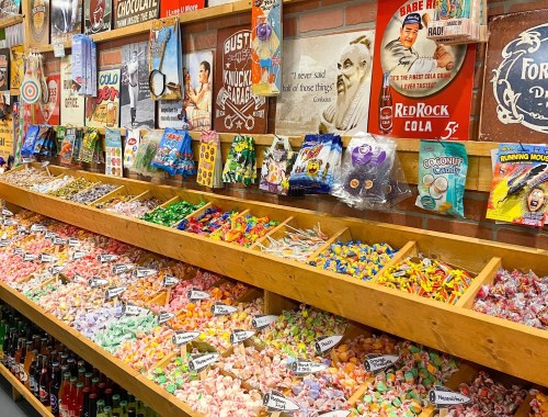 A colorful candy shop display with various candies, snacks, and vintage posters on the wall.