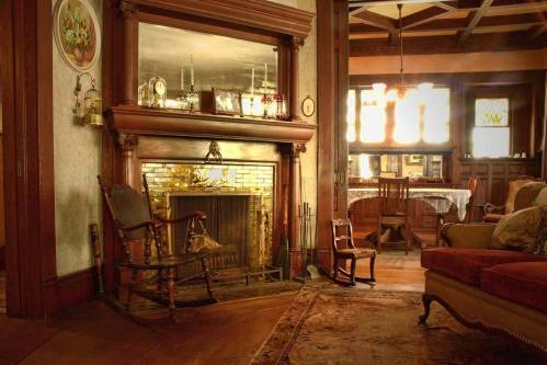 Cozy living room with a fireplace, vintage furniture, and warm lighting, creating an inviting atmosphere.