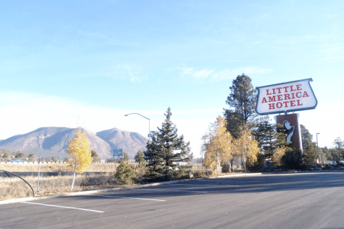 Sign for Little America Hotel with mountains and trees in the background on a clear day.