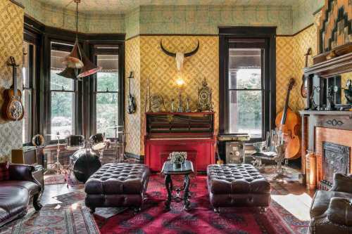 A vintage-style living room with a piano, musical instruments, ornate decor, and plush seating.