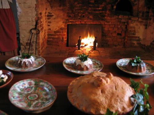A rustic dining table with decorative plates of food in front of a warm, glowing fireplace.