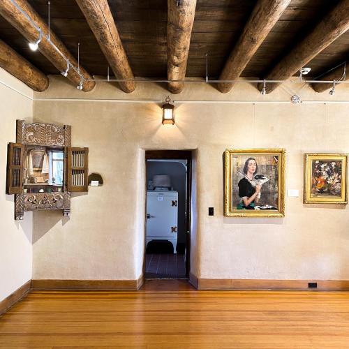 A room with wooden beams, featuring artwork on the walls and a doorway leading to another space.