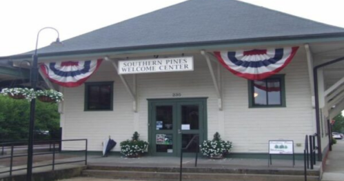 Southern Pines Welcome Center building with patriotic bunting and flower planters at the entrance.