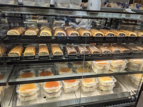 A display case filled with various baked goods, including pastries and desserts in clear containers.
