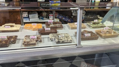 A display case filled with various fudge flavors, each labeled, including chocolate, peanut butter, and mint.