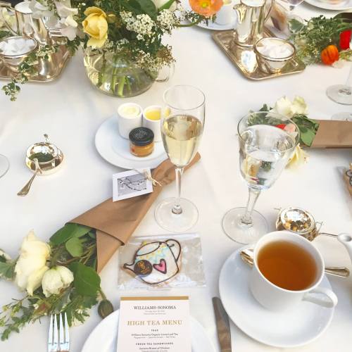 A beautifully set table for high tea, featuring flowers, tea cups, and a menu card.